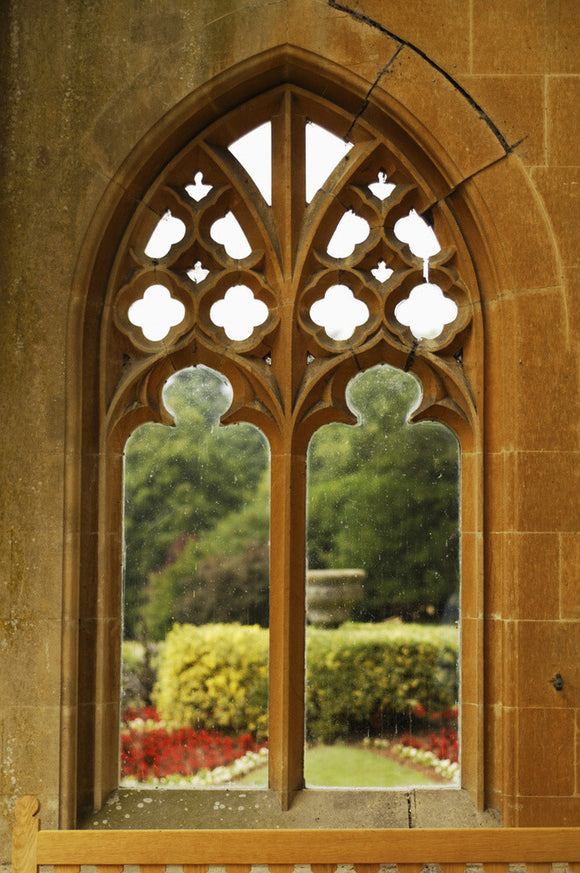A view of the terrace garden planting through the tracery of one of the stone windows of the porch at Tyntesfield, Wraxall, North Somerset