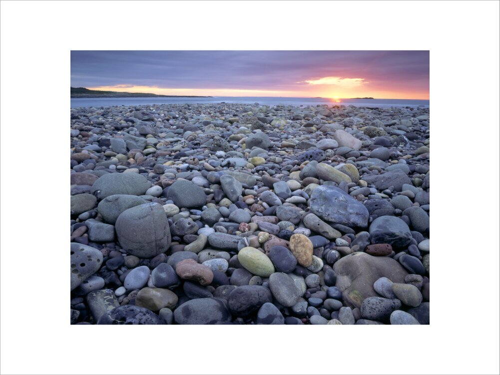 A view of a pebble beach towards the sea, the pebbles are a variety of ...