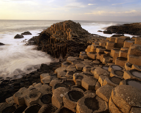 A coastal view taken at the Giant's Causeway, with the sea in motion and the unusual rock formations towered up in the foreground