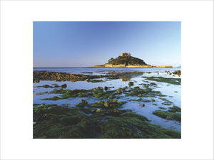 A view looking beyond the rocks on the beach and out to sea at St Michael's Mount with blue sky and sea