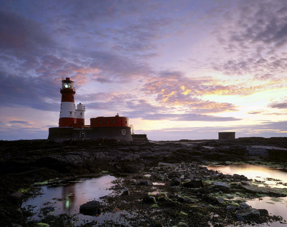 A view of Longstone Lighthouse across a rocky area with pools of water