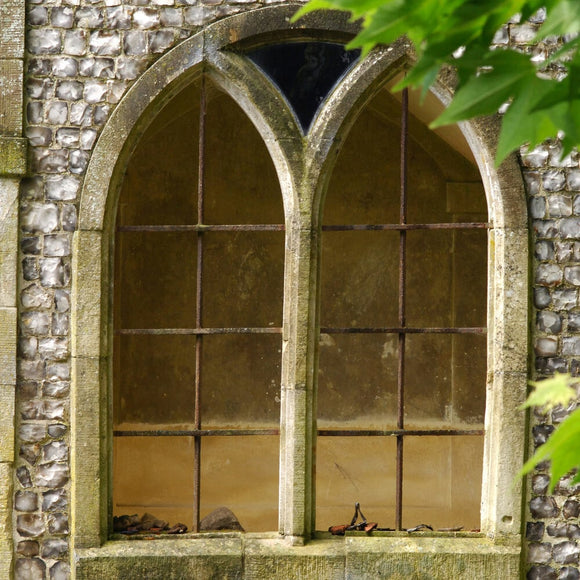A double arched window with stone mullions, set into a flint wall at Mottisfont Abbey