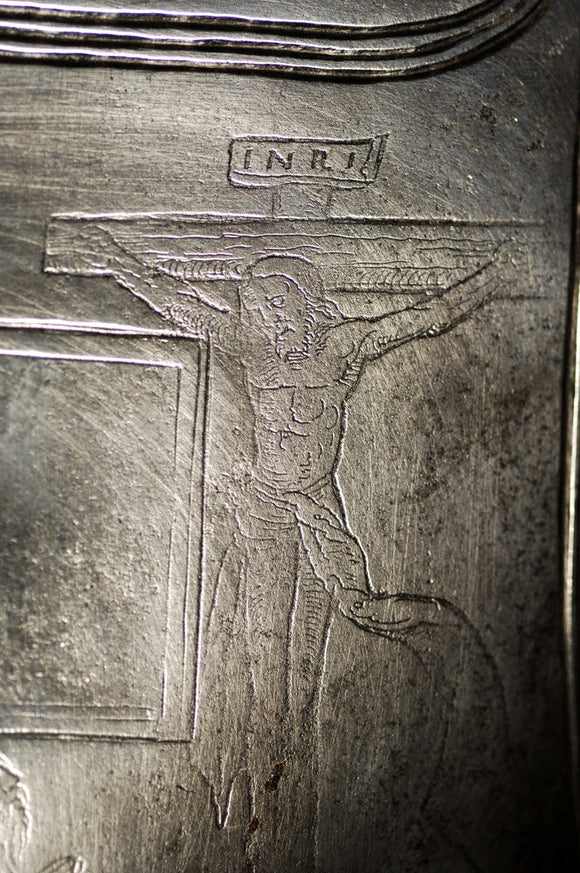 Close view of a German breastplate of 1540 engraved with a crucifix and kneeling knight, in Dragon at Snowshill Manor