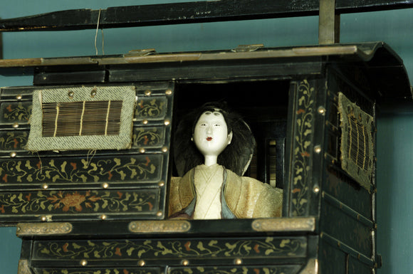 Close view of a Japanese model of a palanquin (litter) with a figure inside, part of Charles Paget Wade's collection, in the Turquoise Hall at Snowshill Manor, Gloucestershire