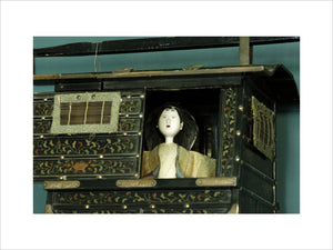 Close view of a Japanese model of a palanquin (litter) with a figure inside, part of Charles Paget Wade's collection, in the Turquoise Hall at Snowshill Manor, Gloucestershire