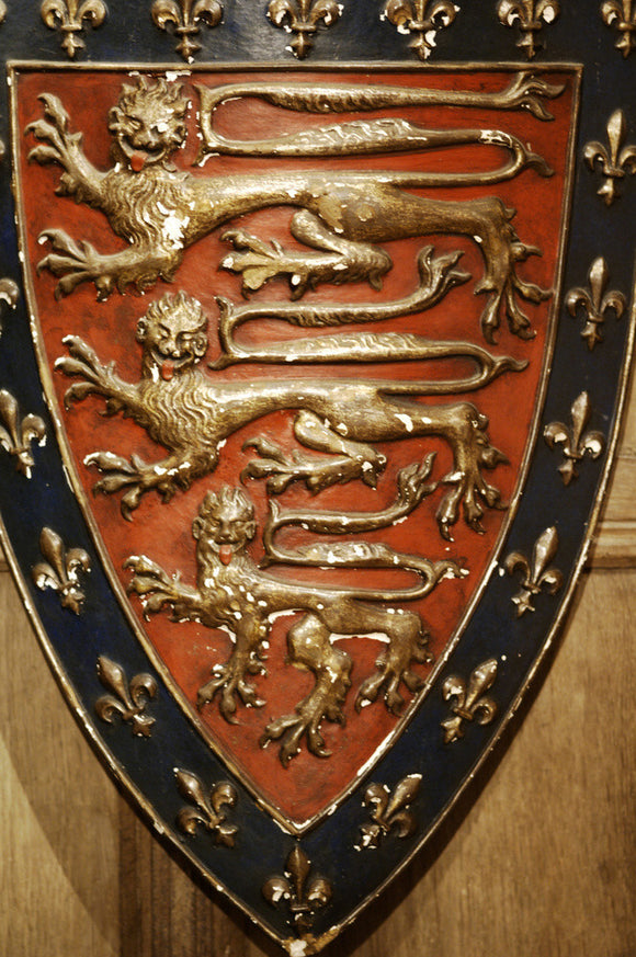Close view of a moulded and painted shield with three gold lions on a red background, in Meridian at Snowshill Manor, home of collector Charles Wade