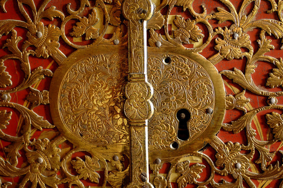 Close view of the lock detail of a French, red lacquered cabinet in the Grey Room at Snowshill Manor