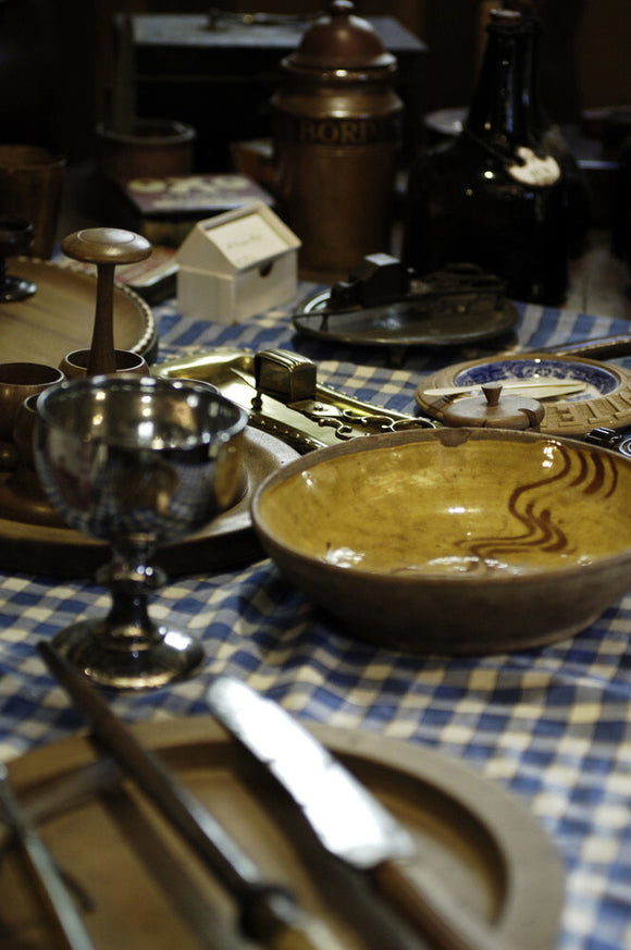 The Jacobean refectory table laid with plates and utensils, part of the collection in the Living Room at the Priest's House, Snowshill Manor