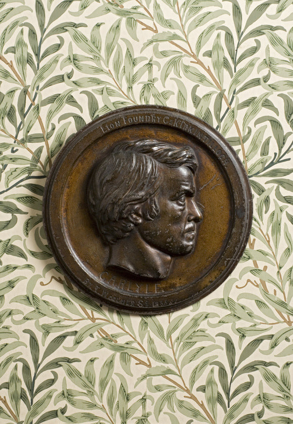 Bronze bas-relief plaque of Thomas Carlyle by Thomas Woolner, 1855, against the William Morris wallpaper 