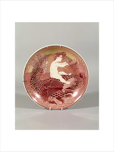 One of a set of six red lustre chargers by de Morgan, depicting a boy on a dolphin