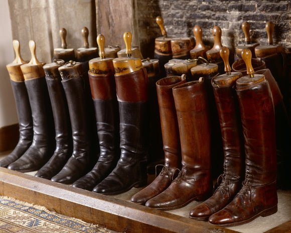 Leather boots lined up in the fireplace of the front stairs at Great Chalfield Manor, near Melksham, Wiltshire