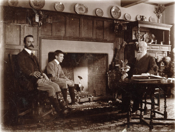 Sepia photograph of Alfred, Joseph and Graham Baron Ash seated around the fireplace in the Hall, in the Lookout Room at Packwood House