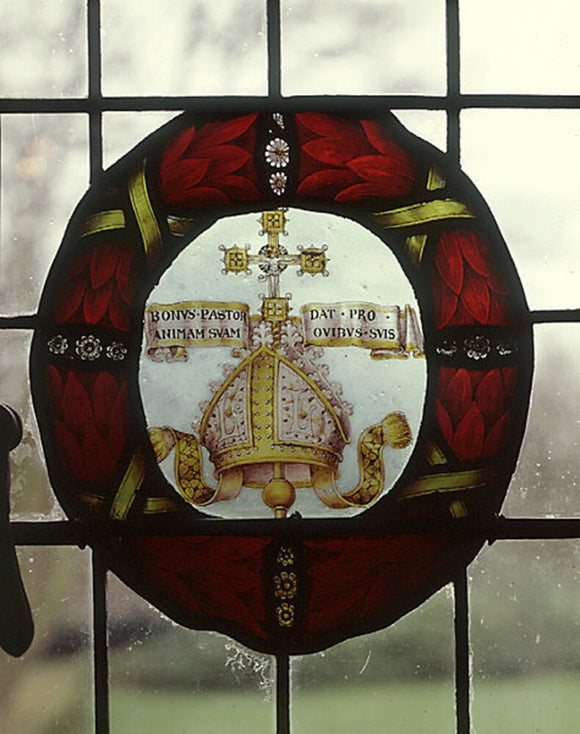 A bishop's mitre, bearing the letters LL with a latin inscription, one of four roundels of painted glass from the Oak Room at Wightwick Manor