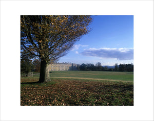 A distant view of the west front of Petworth House, seen across the grass