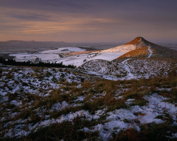 A panoramic view of a snowy Roseberry Common, with the prominent Topping, catching the early morning sun and the horizon lost in the mist
