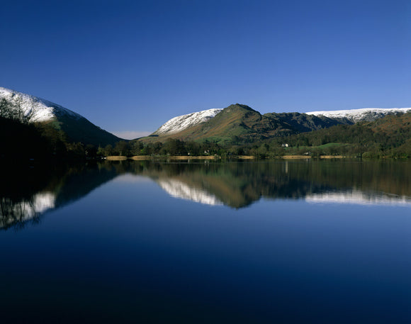 Looking down the length of the lake in Grasmere, to the magnificent snow capped hills in the distance, with the scene reflected in the shimmering water