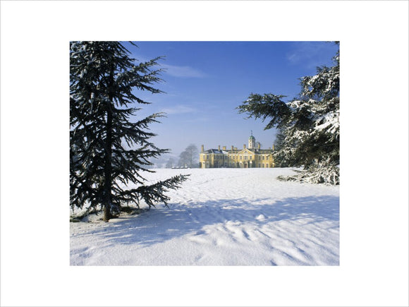 Heavy snowfall at Polesden Lacey, view of the house in the distance with fir trees in the foreground in February 1991