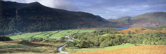 Overall view of Buttermere Valley showing the lake at the end of the valley with a river and a farm, bracken in the foreground and two hilly ranges behind