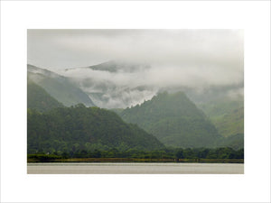 Castle Crag (a conical wooded hill) on a misty summer morning from the east shore of Derwentwater, Cumbria
