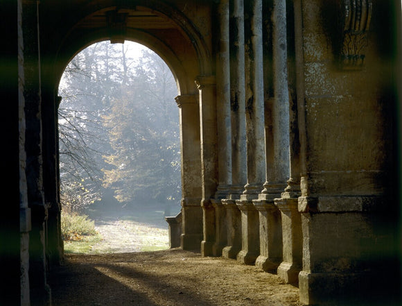 The C18th Palladian Bridge at Stowe Landscape Gardens with light coming through the arch and trees in the background