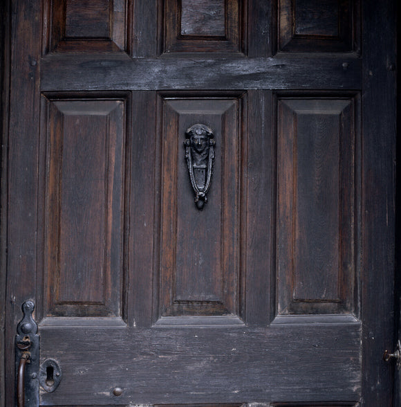 Close shot of the fielded panels of the oak front door and cast-iron door knocker at Hill Top, the home of Beatrix Potter in Sawrey, Cumbria