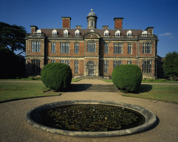 The south front of Sudbury Hall standing out against the blue sky, with the lily pond in the foreground