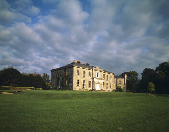 The West Front of the Argory seen from across the lawn with stormy sky behind