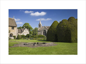 A view across the large lawn at the fifteenth-century Great Chalfield Manor, Wiltshire, with the yew house on the right hand side and the Parish Church of All Saints in the centre