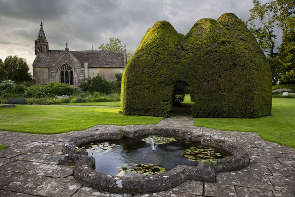 The C14th century Paris Church of All Saints, seen across the lily pond at Great Chalfield Manor, Wiltshire
