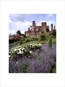 The east front of Standen seen from the garden, with purple and white flowers in the foreground