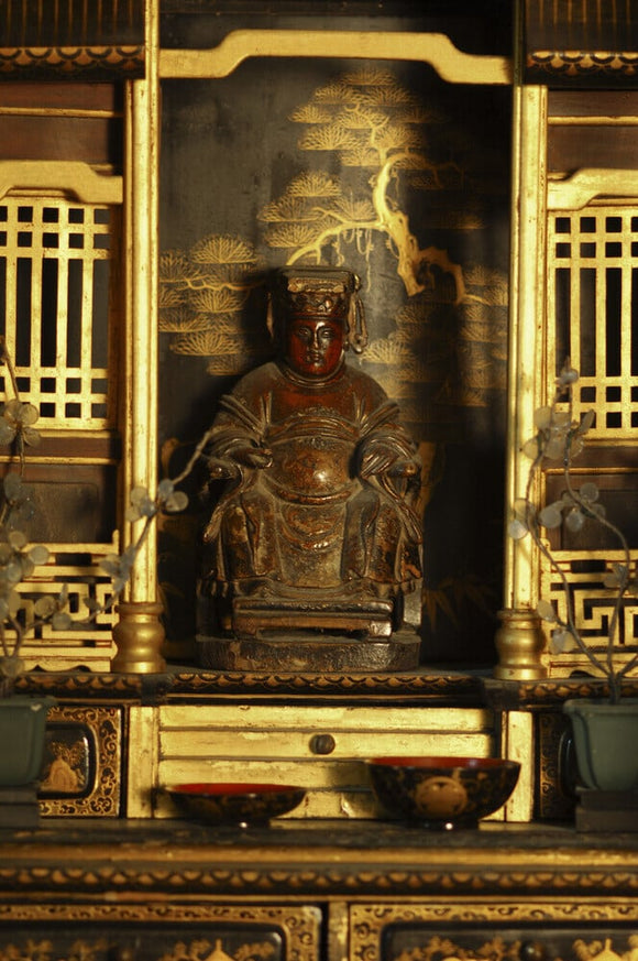 Carved wooden figure, seated on a throne, part of the Charles Wade collection in the Green Room at Snowshill Manor, Gloucestershire