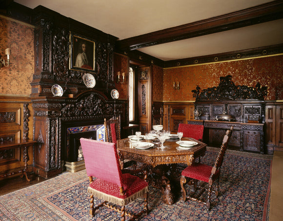 View of the Small Dining Room at Oxburgh Hall showing the table, chairs, fireplace and large wooden buffet