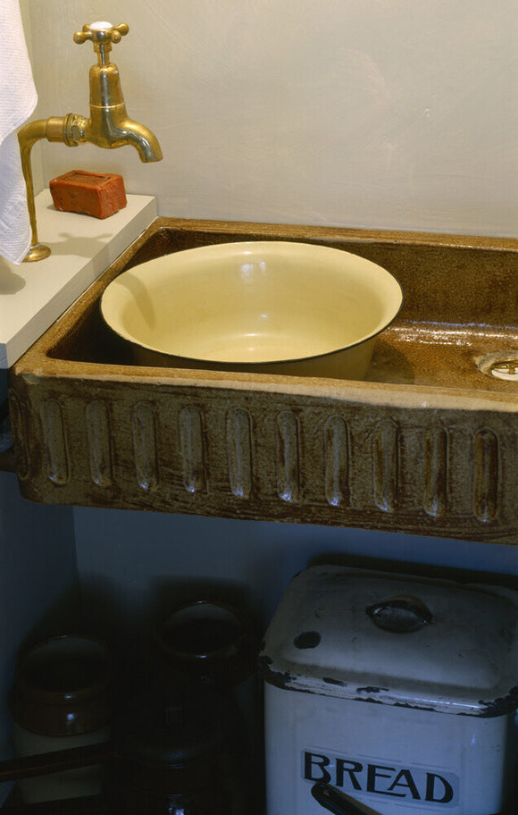 A brownstone sink in the 1930s scullery, next to a Living Room in the Birmingham Back to Backs