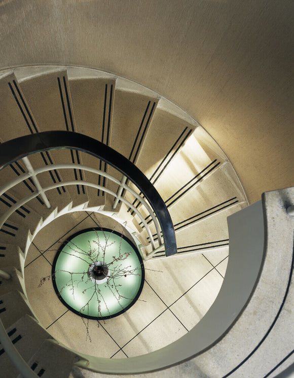 A view looking down the striking spiral staircase at The Homewood designed by Patrick Gwynne is made of concrete with a terrazzo finish and illuminated by a large sunken uplighter at the base
