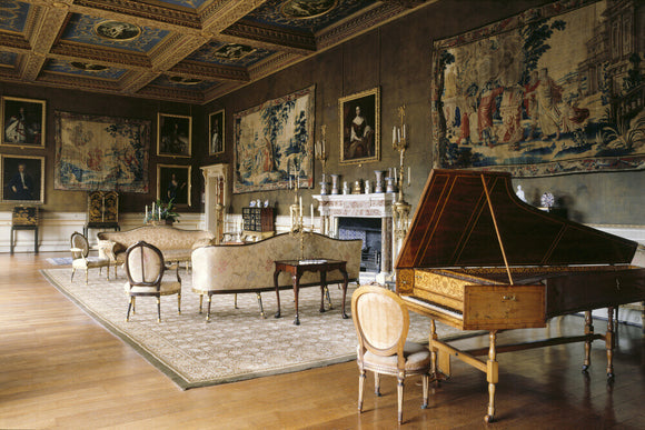 View of the Saloon at Chirk Castle, showing the harpsichord, chimneypiece and serpentine settees with matching oval-backed chairs, as well as the four 17th century Mortlake tapestries
