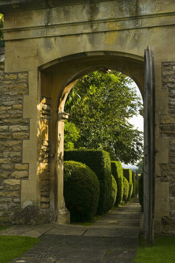 View through the stone entrance arch towards the topiary-flanked path at Westwood Manor