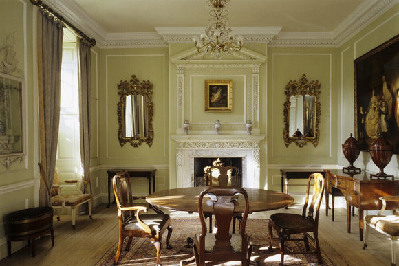 The Dining Room at Peckover House showing the C18th dining table and chairs and a two-tier chimneypiece set into the panelling from the same date
